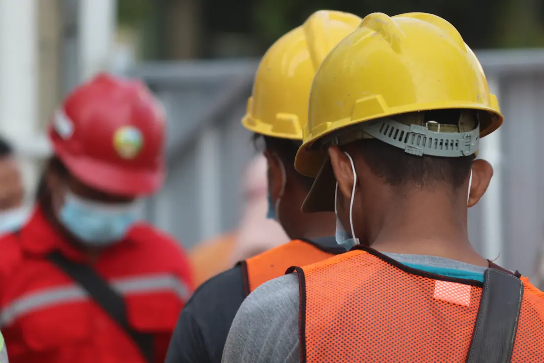 Trabajadores con casco y chaleco de seguridad en su jornada